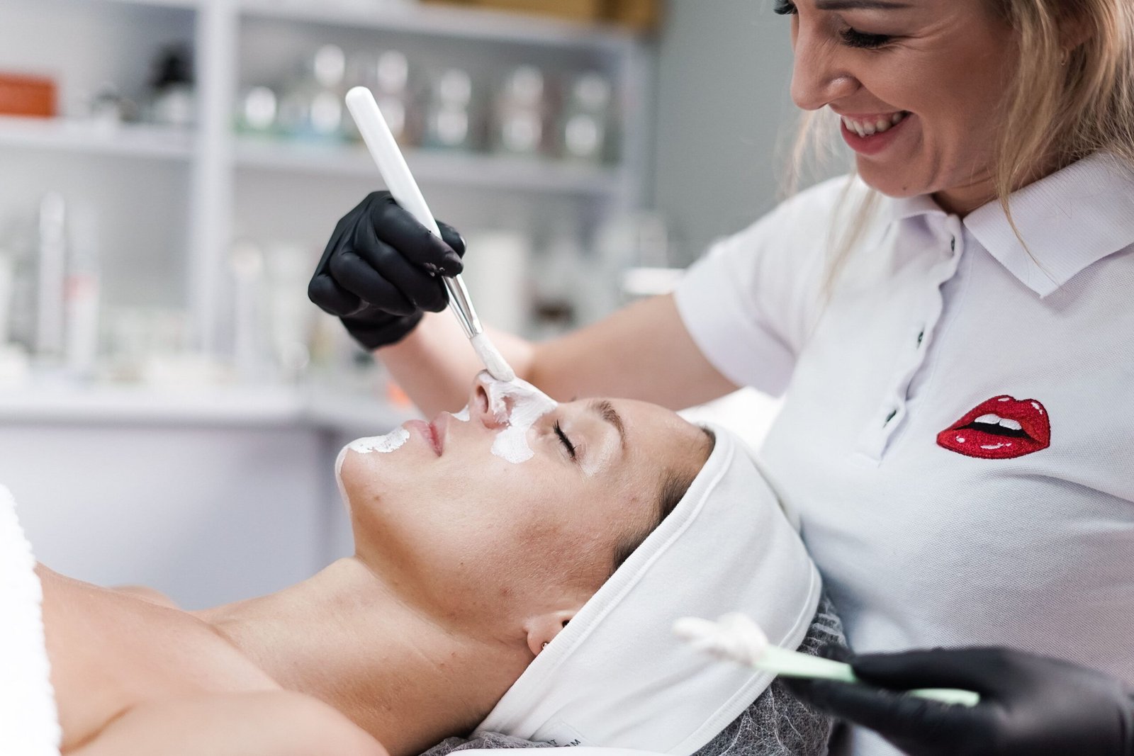 Professionnelle réalisant un soin du visage avec des gants et un pinceau propre